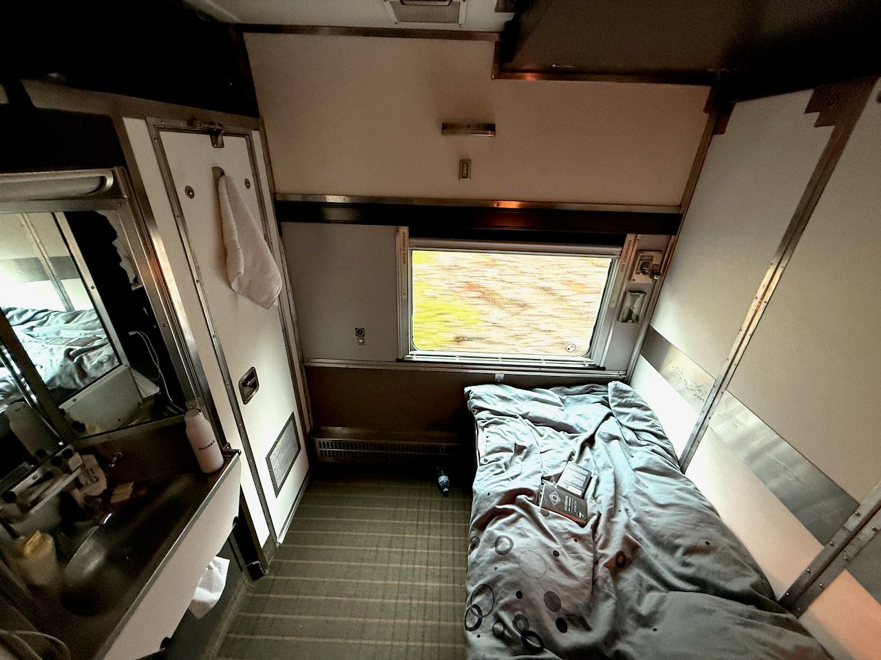 Cozy train sleeper cabin interior with bed and window view.