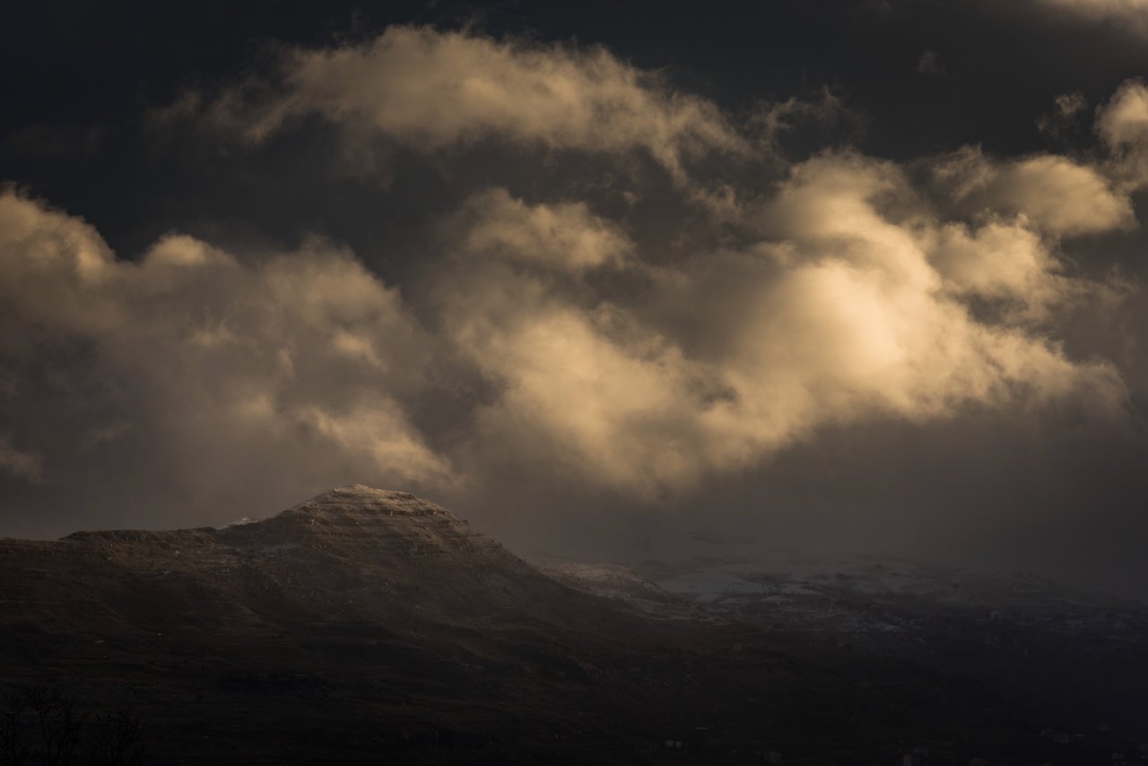 Dramatic cloudy sky over a mountain peak at dusk.