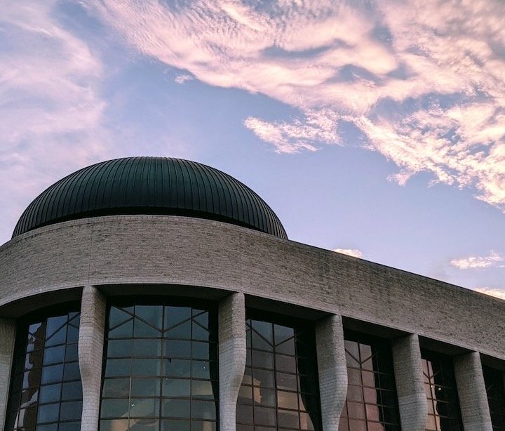 A futuristic building with domed rooftops under a pastel sunset sky.