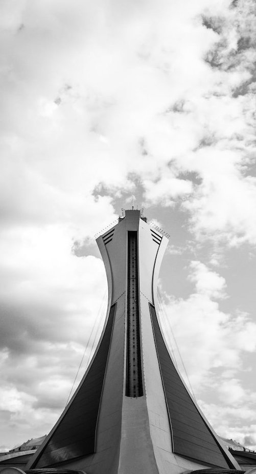 A black-and-white image of a modern architectural structure extending into the sky.