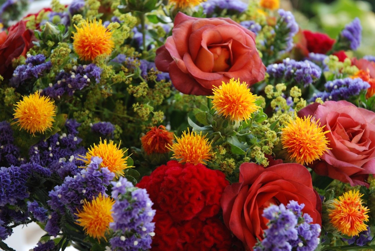 Vibrant mixed flower bouquet with roses, safflowers, and statice.