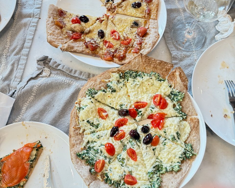Flatbread pizza with olives, mushrooms, spinach and cheese on dining table