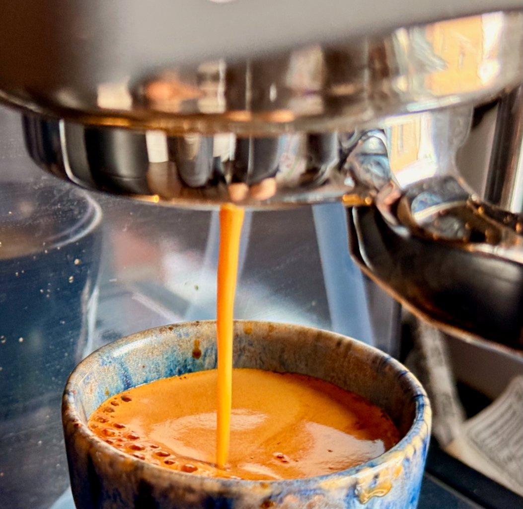 Close-up of espresso pouring into a ceramic cup