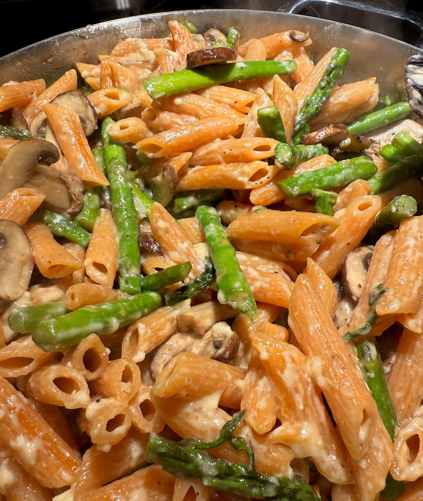 Creamy pasta with asparagus and mushrooms in a skillet