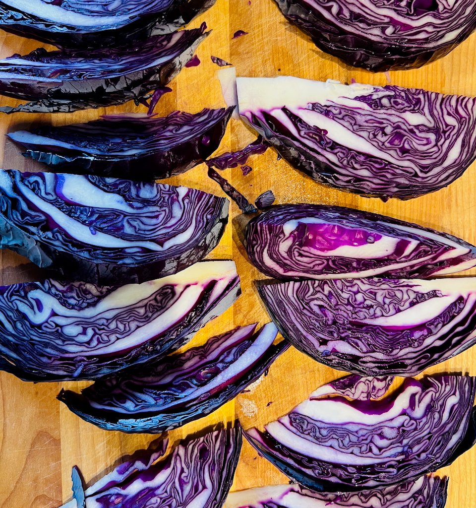 Freshly cut red cabbage pieces arranged on a wooden cutting board