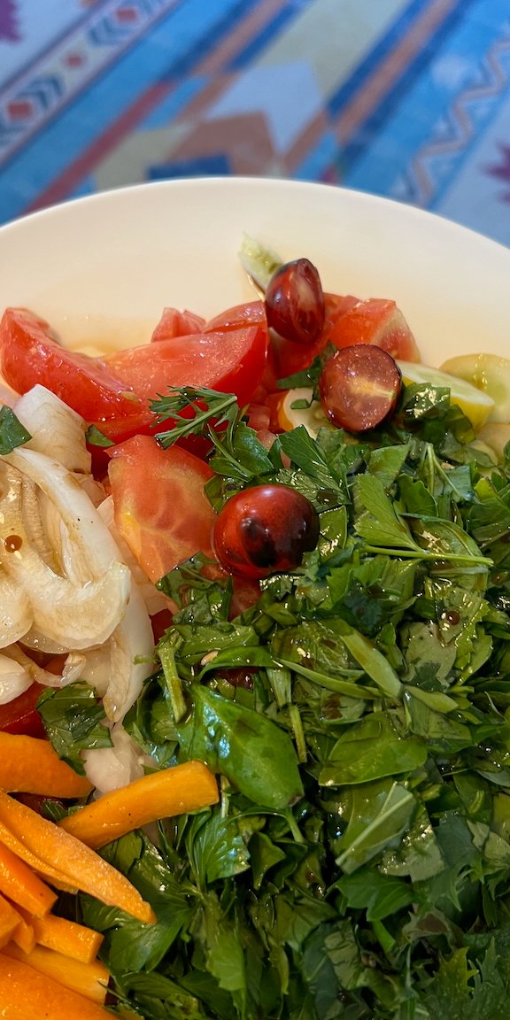 Fresh salad with tomatoes, carrots, parsley, and onions on a plate