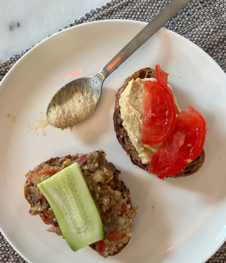 Open-faced toasts with eggplant salad, hummus, and sliced vegetables
