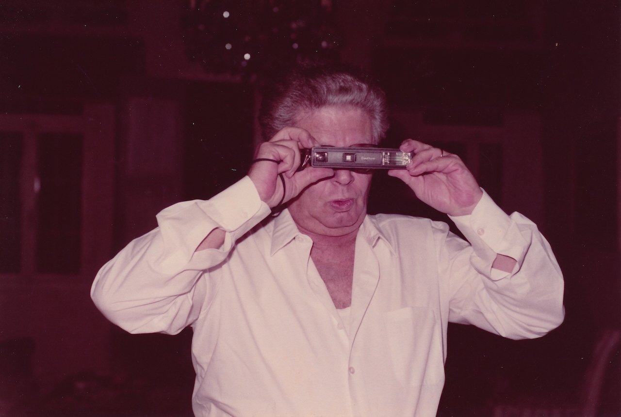 Person using vintage Kodak camera with a playful expression.