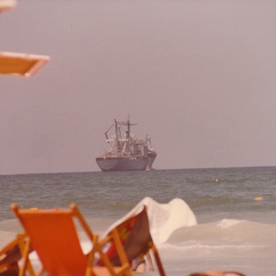 Ship on the horizon with beach chairs in the foreground.