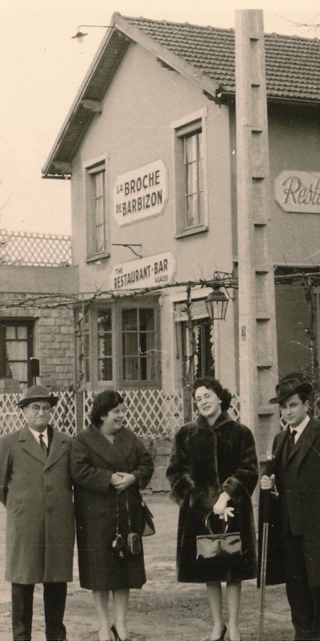 Vintage photo of four people in front of a restaurant, La Broche de Barbizon, showcasing 1960s fashion and style.