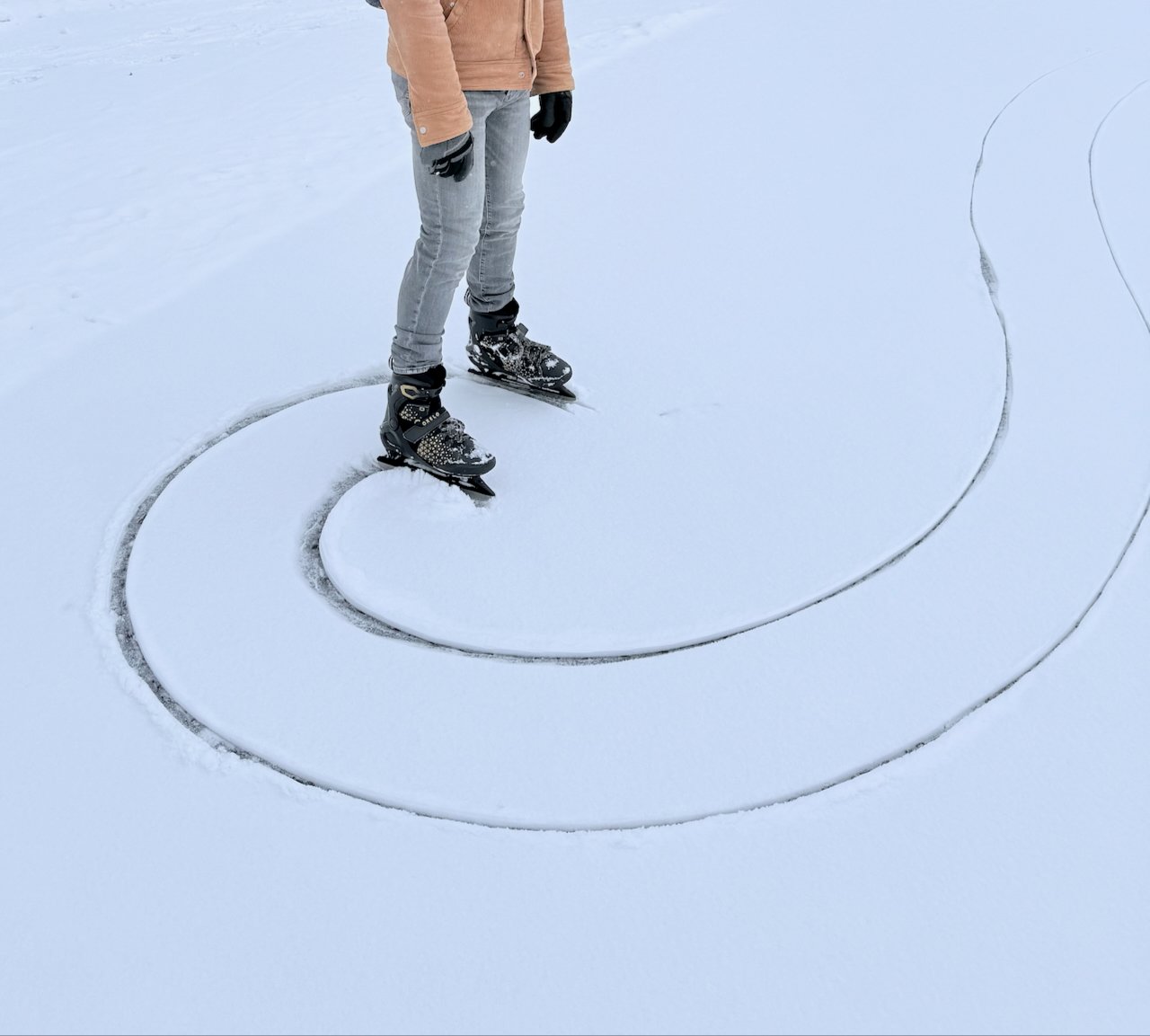 Ice skate tracks forming spiral patterns on fresh snow