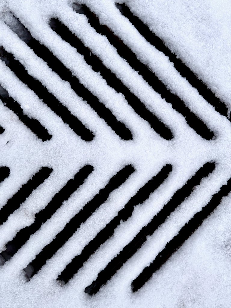 Snow-covered drainage grate with diagonal pattern