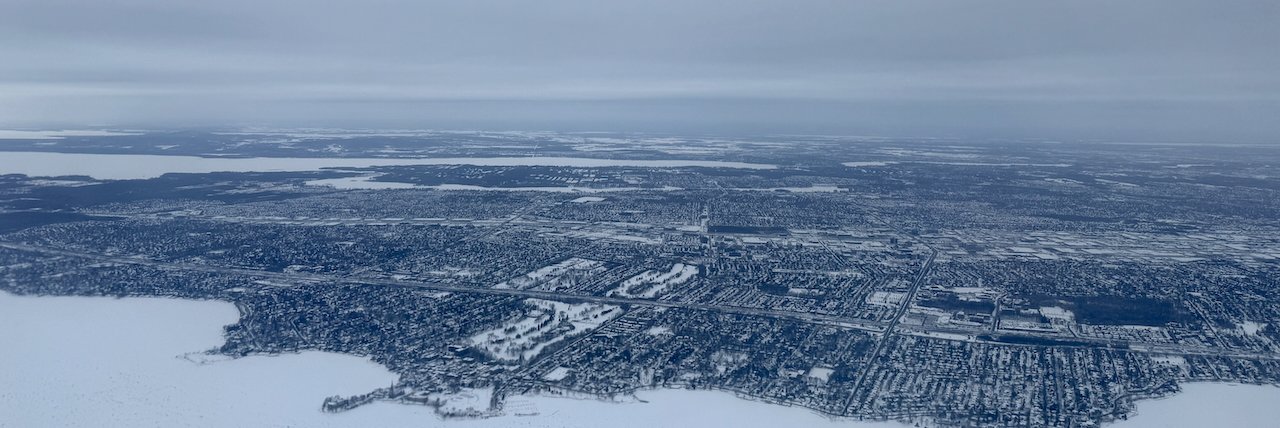 Aerial view of a snowy suburban cityscape under overcast sky